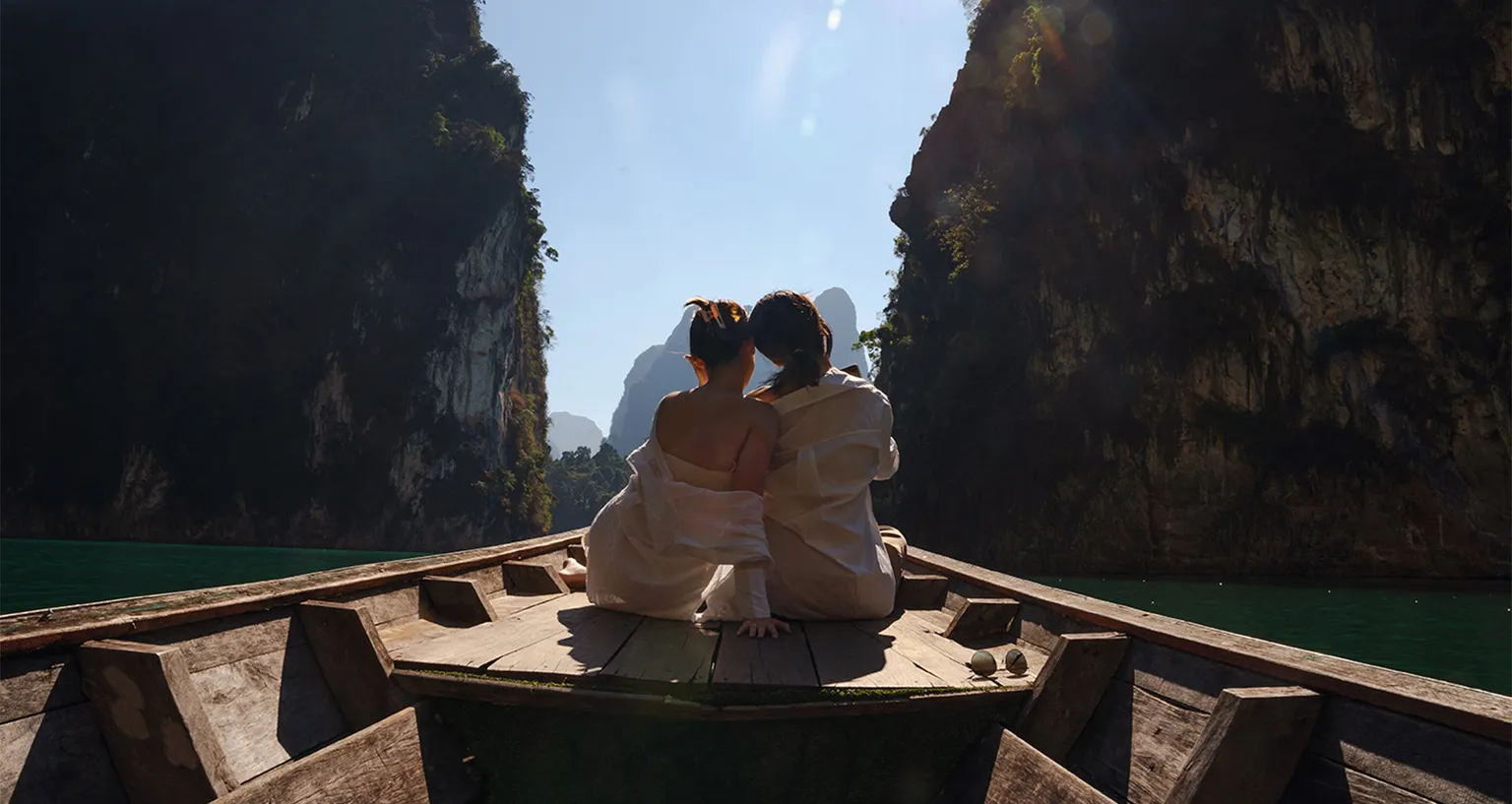 A couple sits together on a boat between limestone cliffs, enjoying a scenic honeymoon destination.