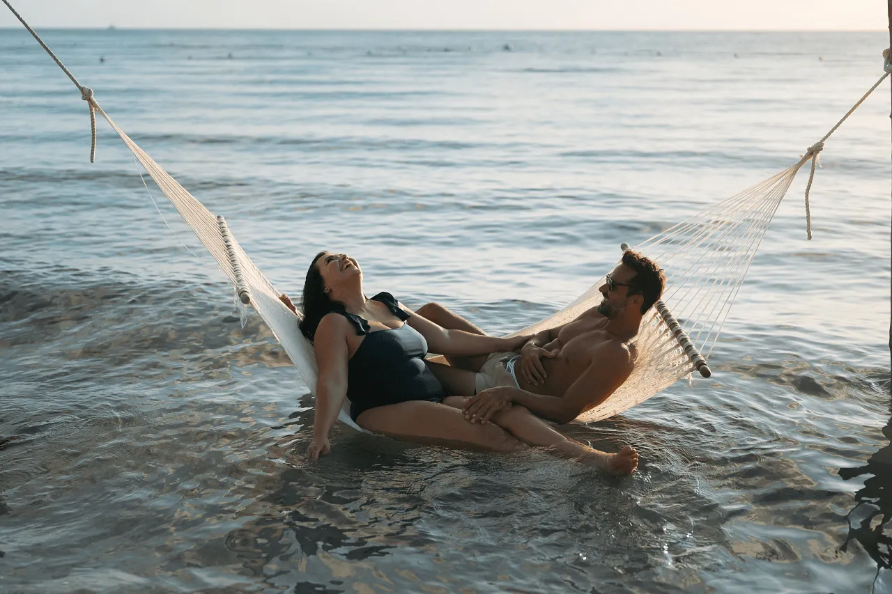 couple sitting in hammock in the water and laughing