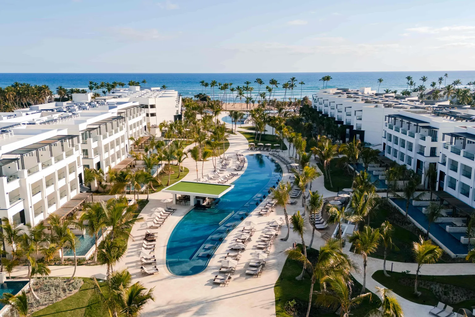 Aerial view of resort property and pool surrounded by palm trees at Secrets Tides Punta Cana.
