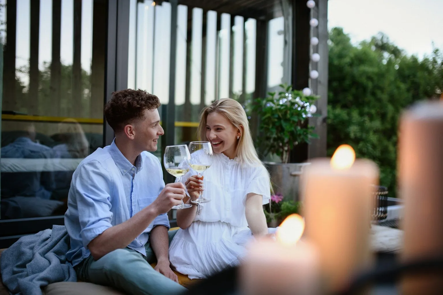 Couple clinking wine glasses while sitting outdoors in the evening.