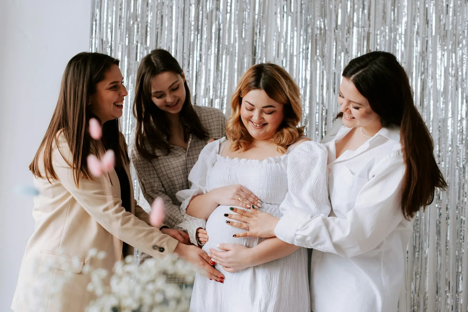 Women smiling together with a pregnant woman at a baby shower.