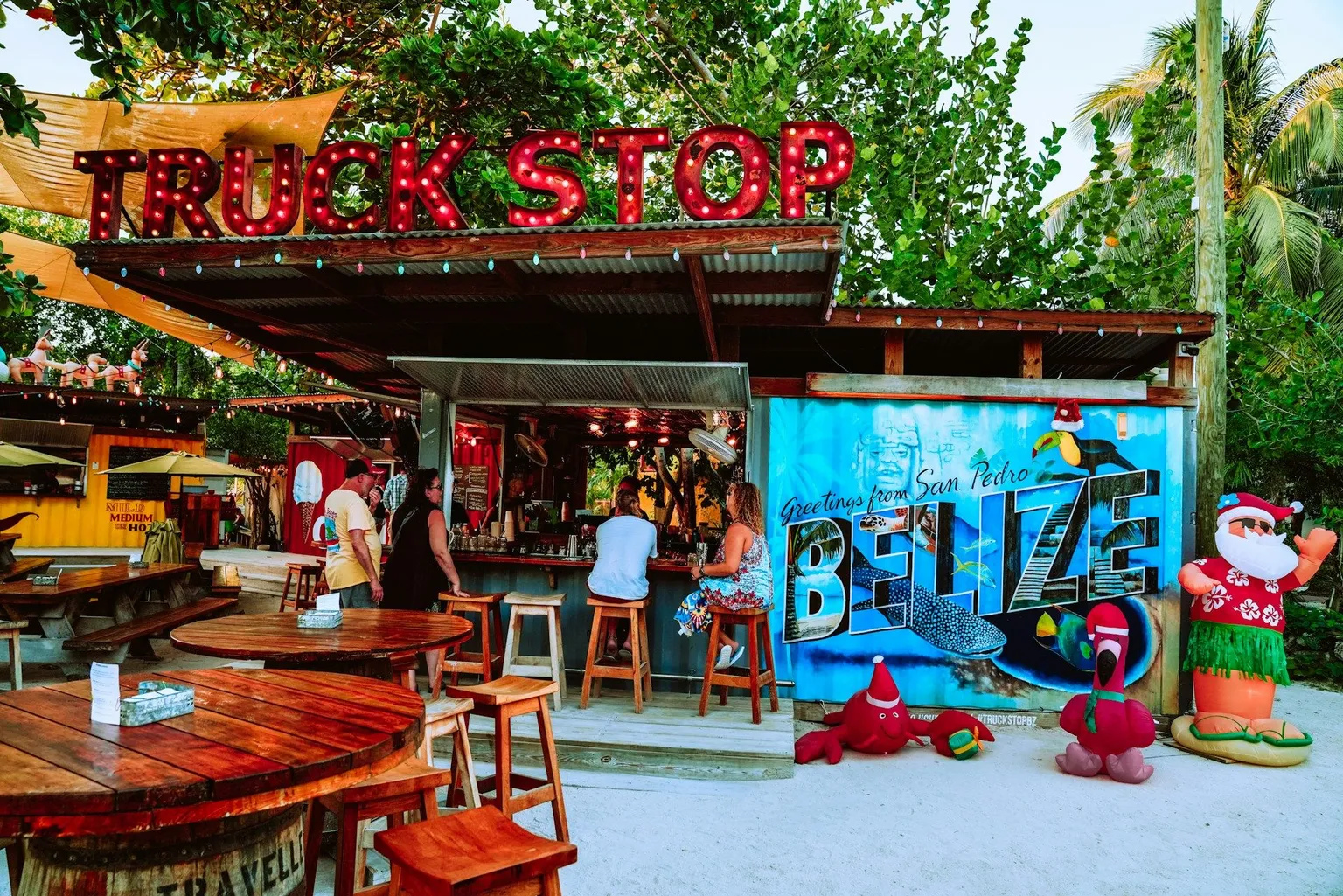 The Truck Stop food and drink container park in San Pedro, Belize, with a colorful Greetings from San Pedro Belize mural.