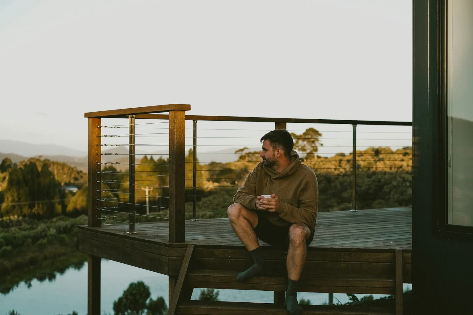 Traveler relaxing on a cabin deck overlooking the Australian landscape at sunset.