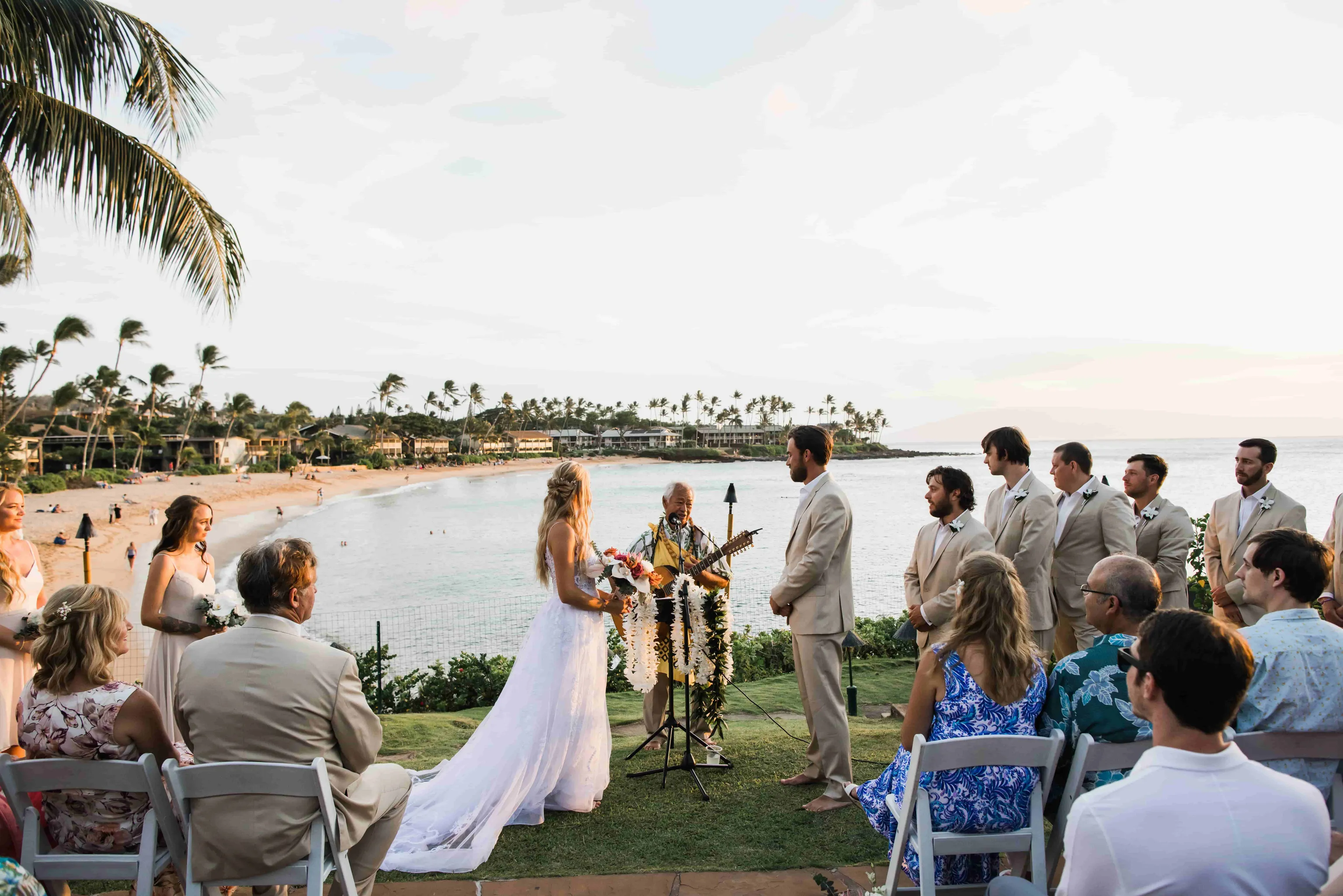 Beachfront wedding ceremony at Napili Kai Beach Resort with ocean view and guests.