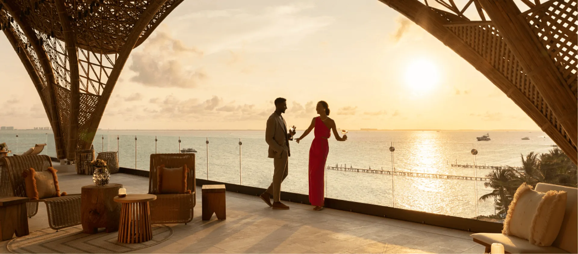 couple standing against glass rail with ocean in background