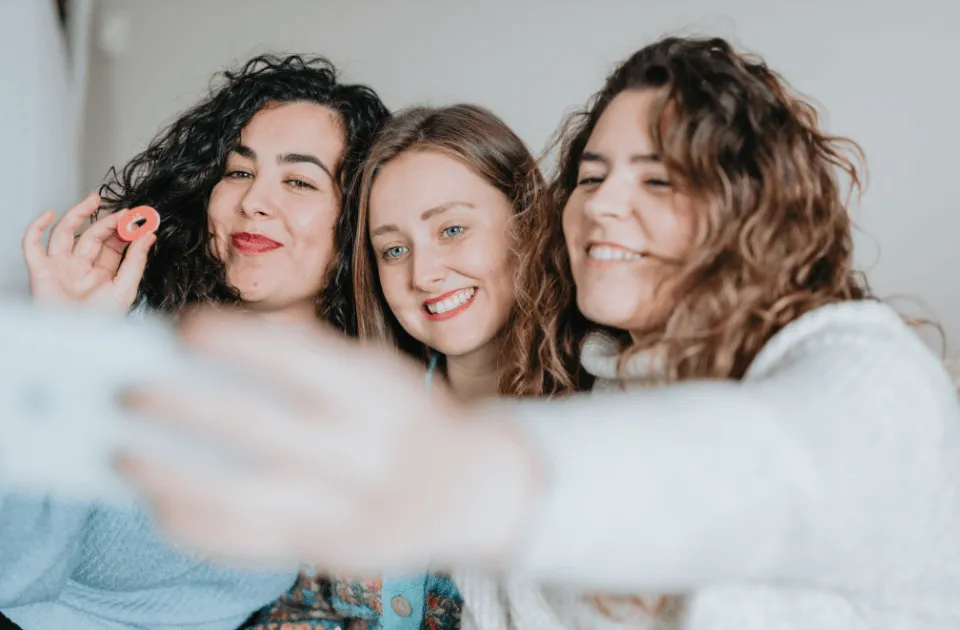 Three women smiling while taking a selfie together.