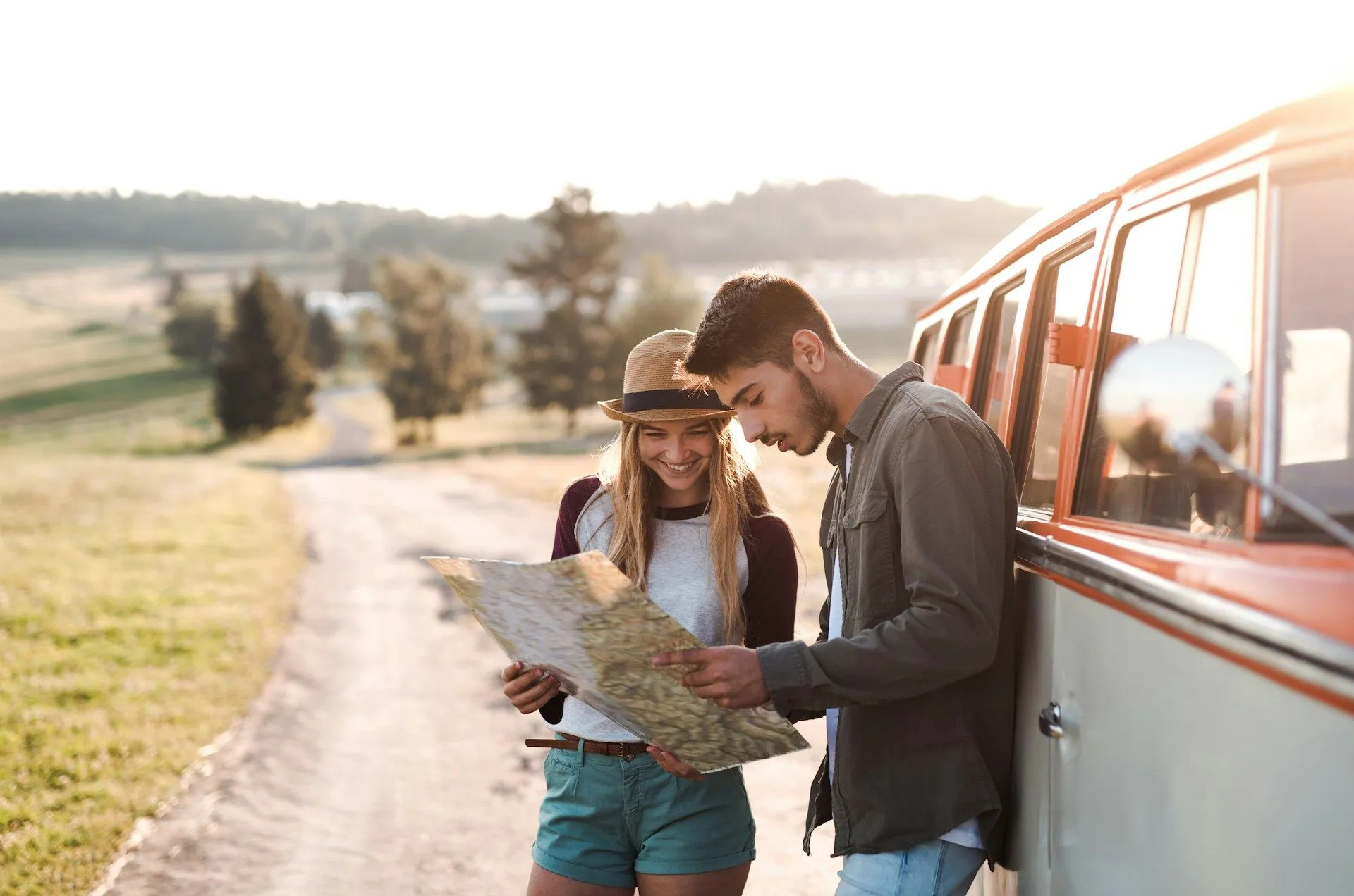 A couple looking at a map standing outside of their car