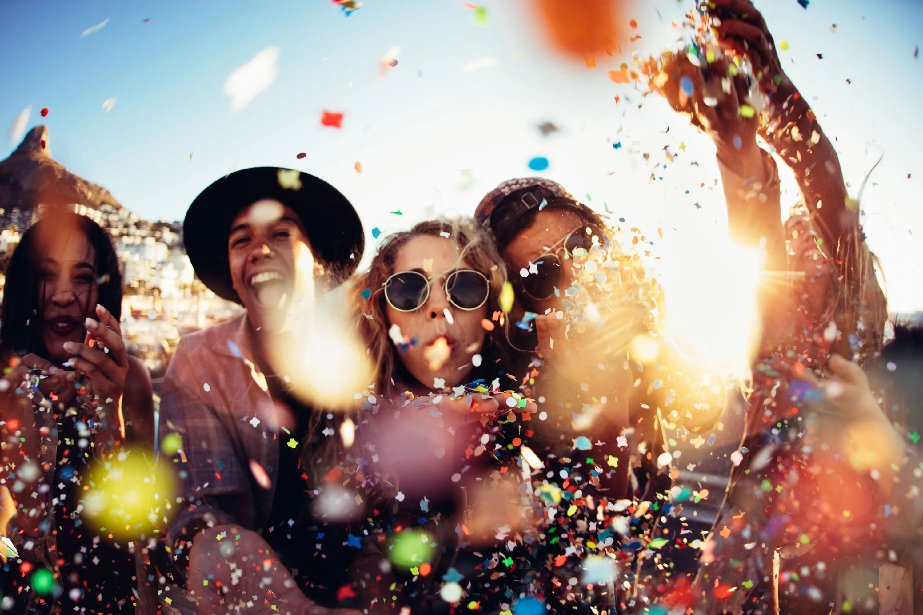 Group of friends celebrating outdoors with colorful confetti.