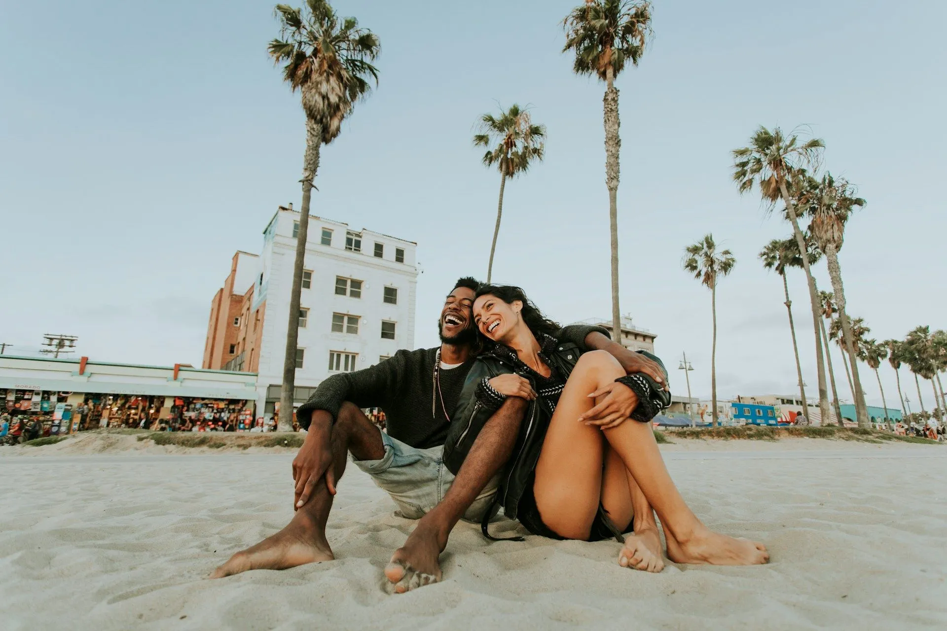 Couple relaxing on the sand at Venice Beach with palm trees in California.