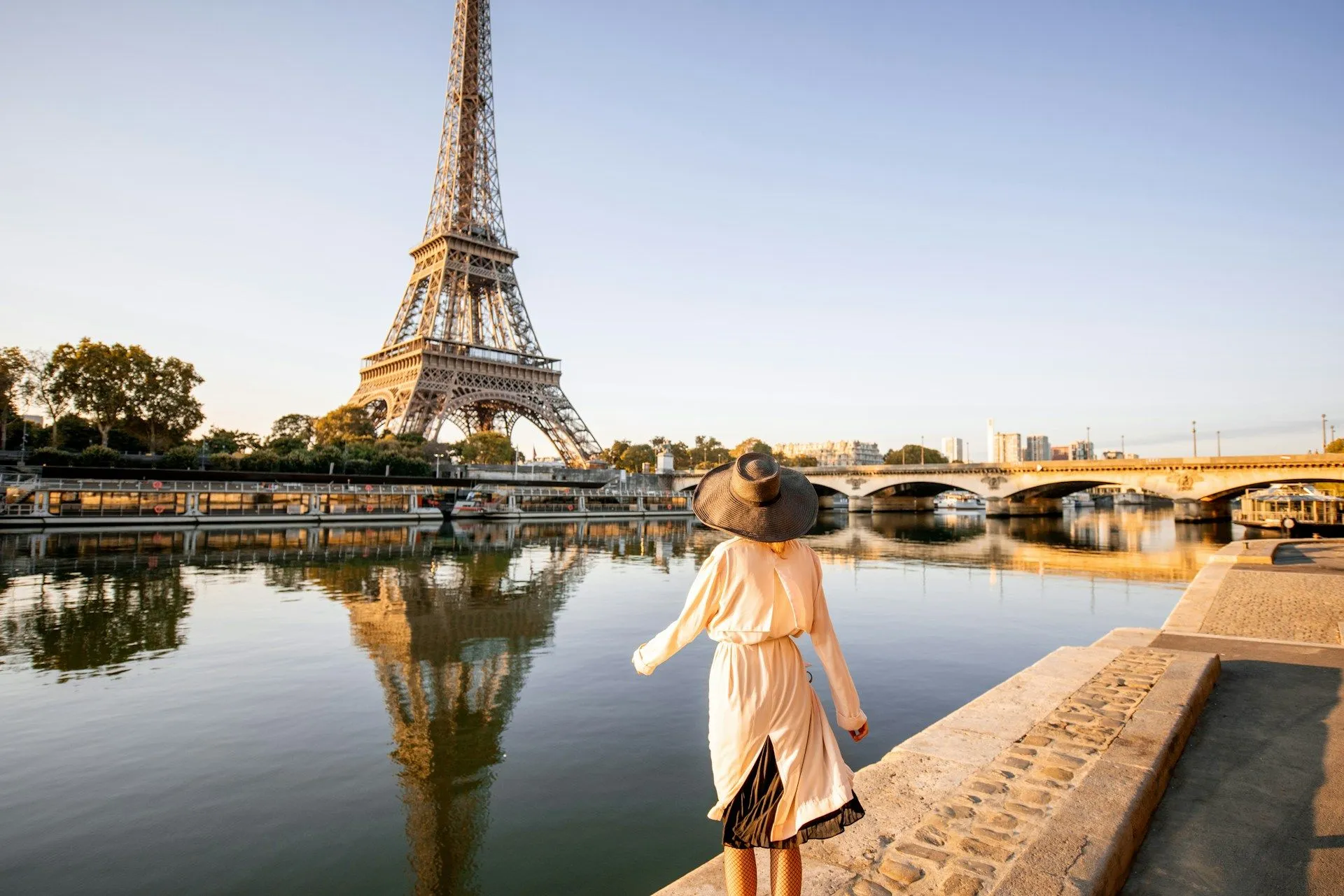 Woman walking along the Seine River with the Eiffel Tower in Paris.