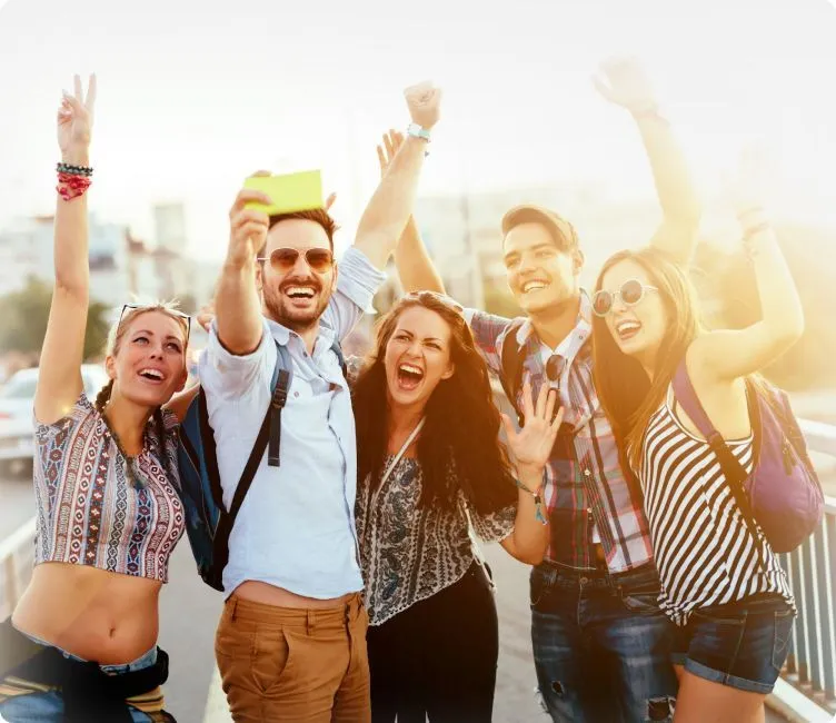 Group of friends celebrating and taking a selfie outdoors during daylight