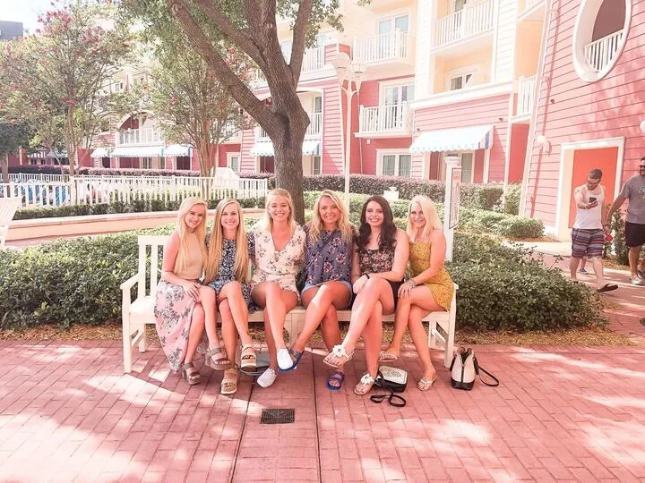six women sitting on disney bench