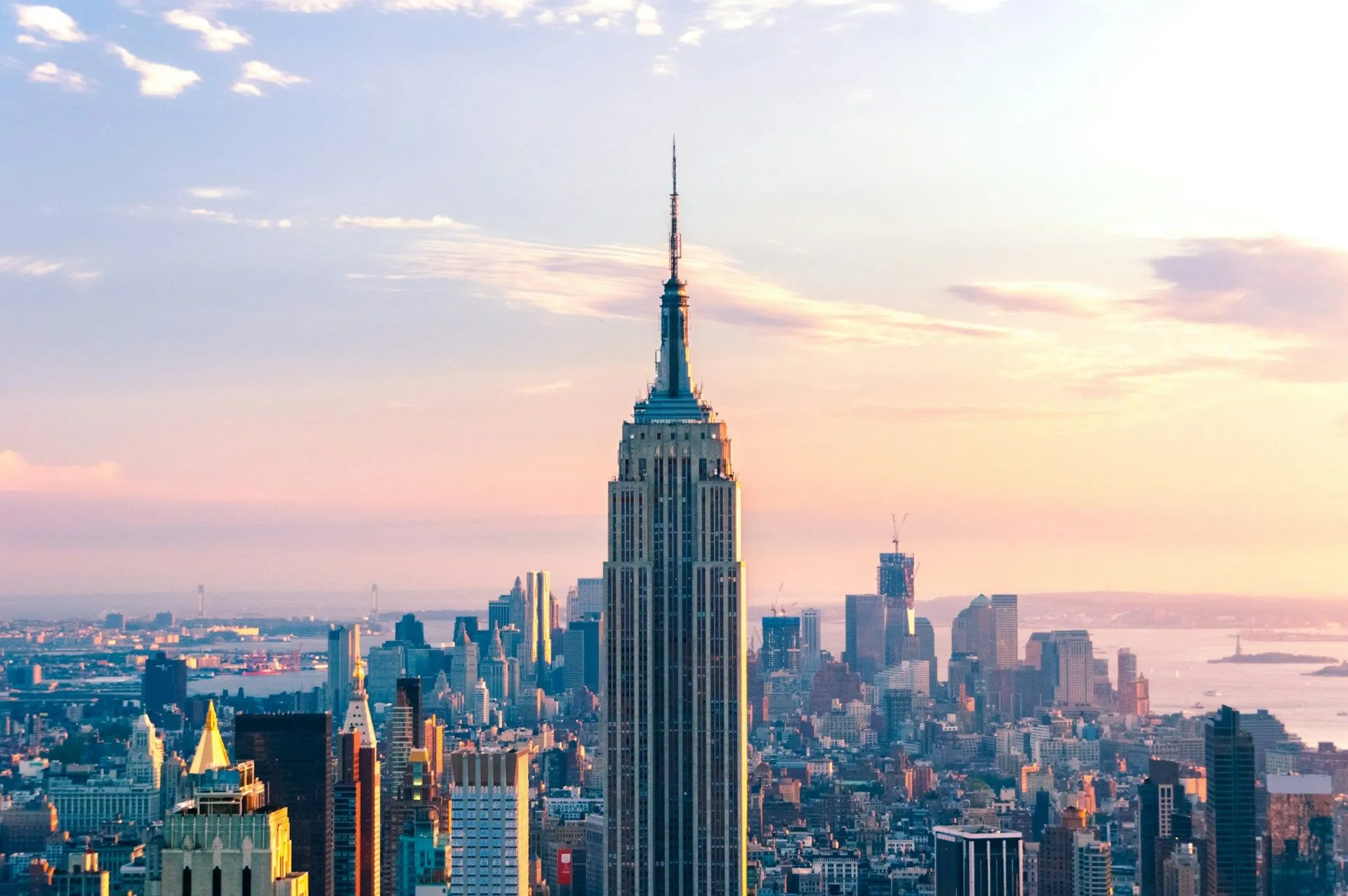 Empire State Building rising above the New York City skyline at sunset.