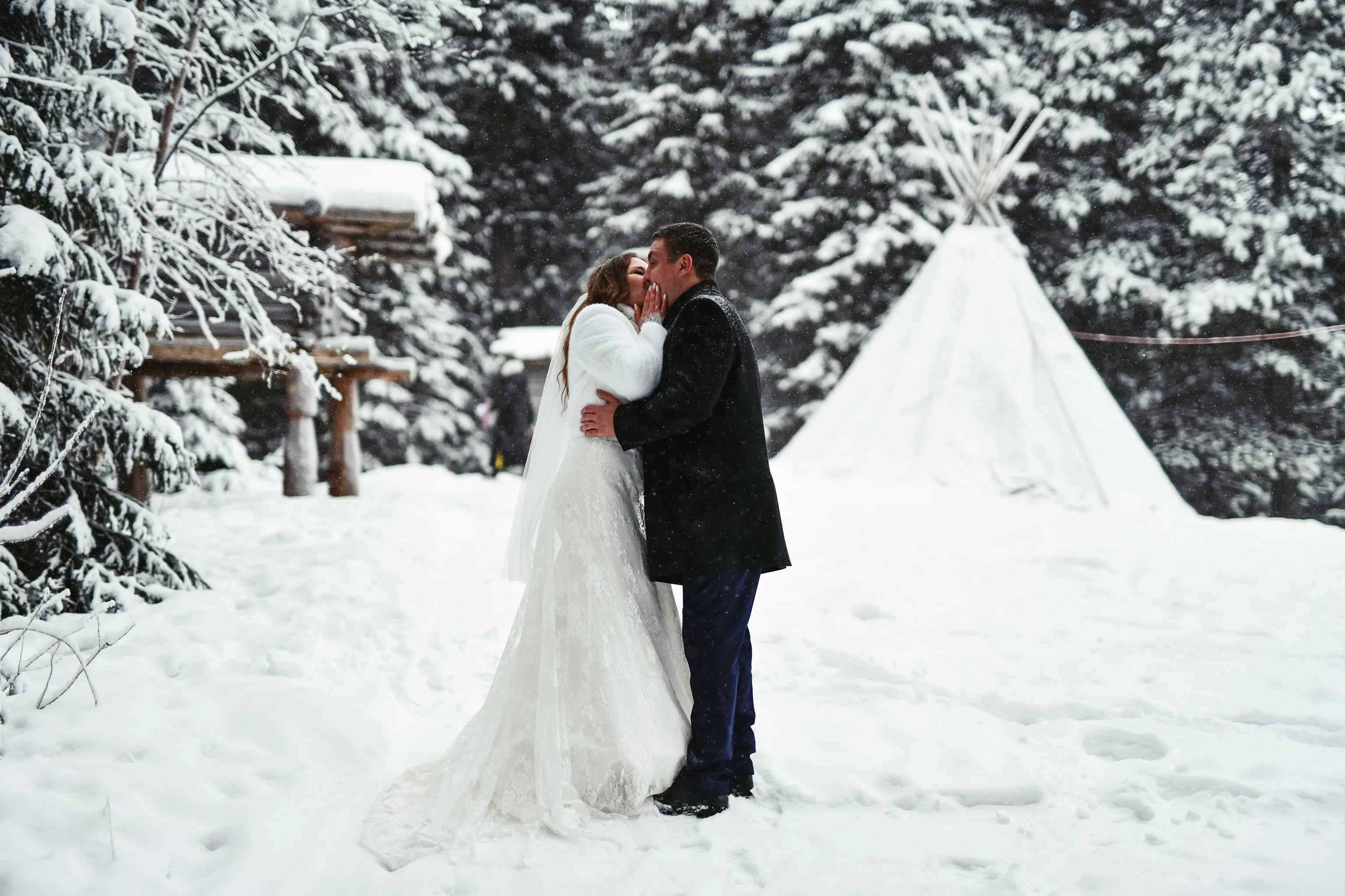 A bride and groom kissing in the snow