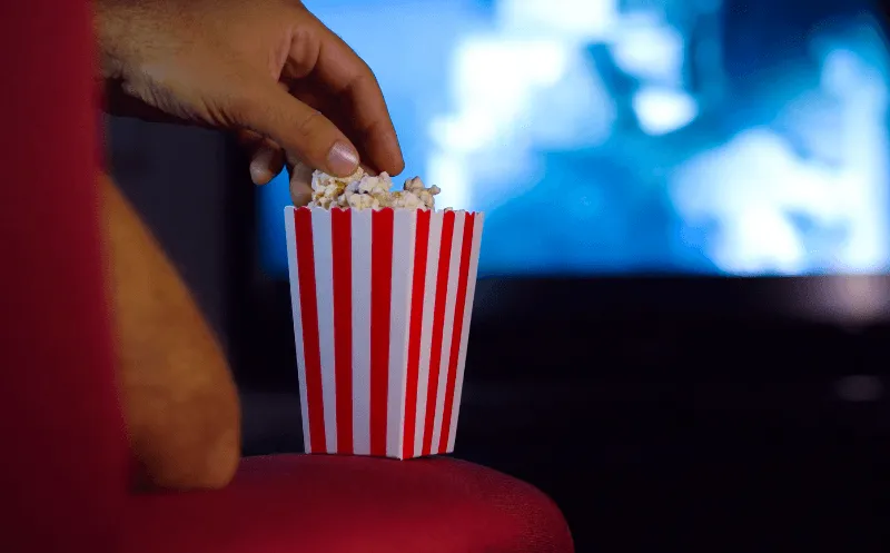A person eating popcorn and watching a movie.