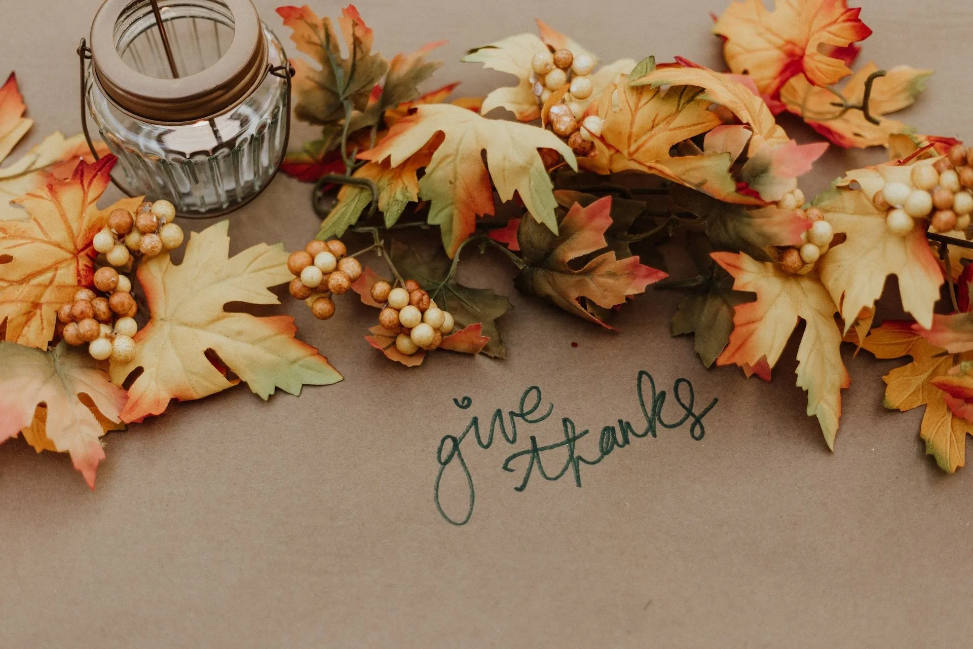 candle and fall table leaves placed above the phrase give thanks written on the table